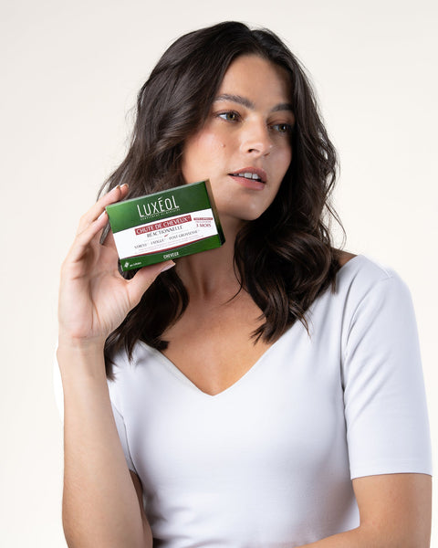 Woman holding a Luxeol product box against a plain background