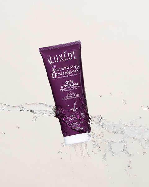 Purple Luxeol shampoo tube on a beige background with water droplets