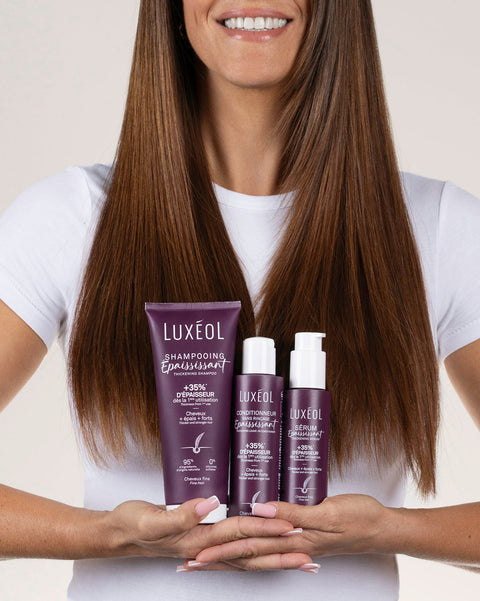 Woman holding Luxeol hair care products with a plain background